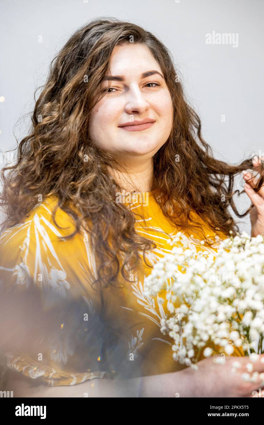 Una ragazza in una T-shirt gialla con un bouquet di piccoli fiori bianchi Foto Stock