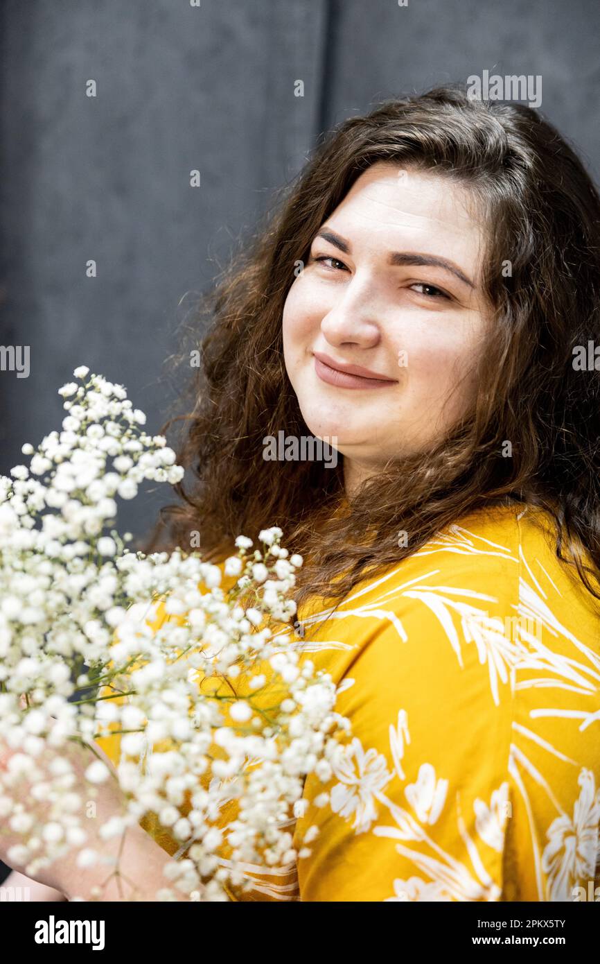 Una ragazza in una T-shirt gialla con un bouquet di piccoli fiori bianchi Foto Stock