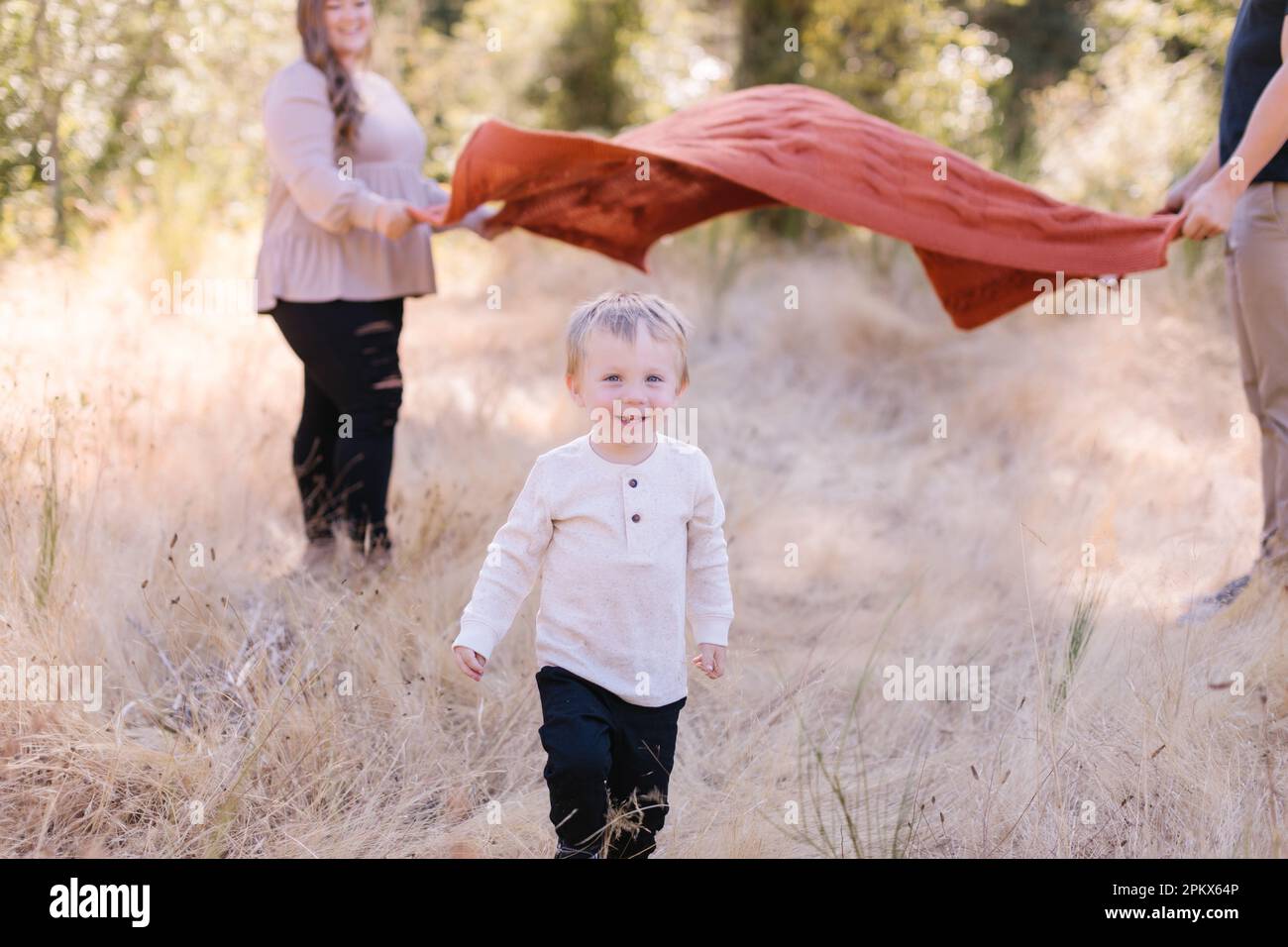 Adorabile bambino che corre sotto coperta mamma e papà tenendo Foto Stock