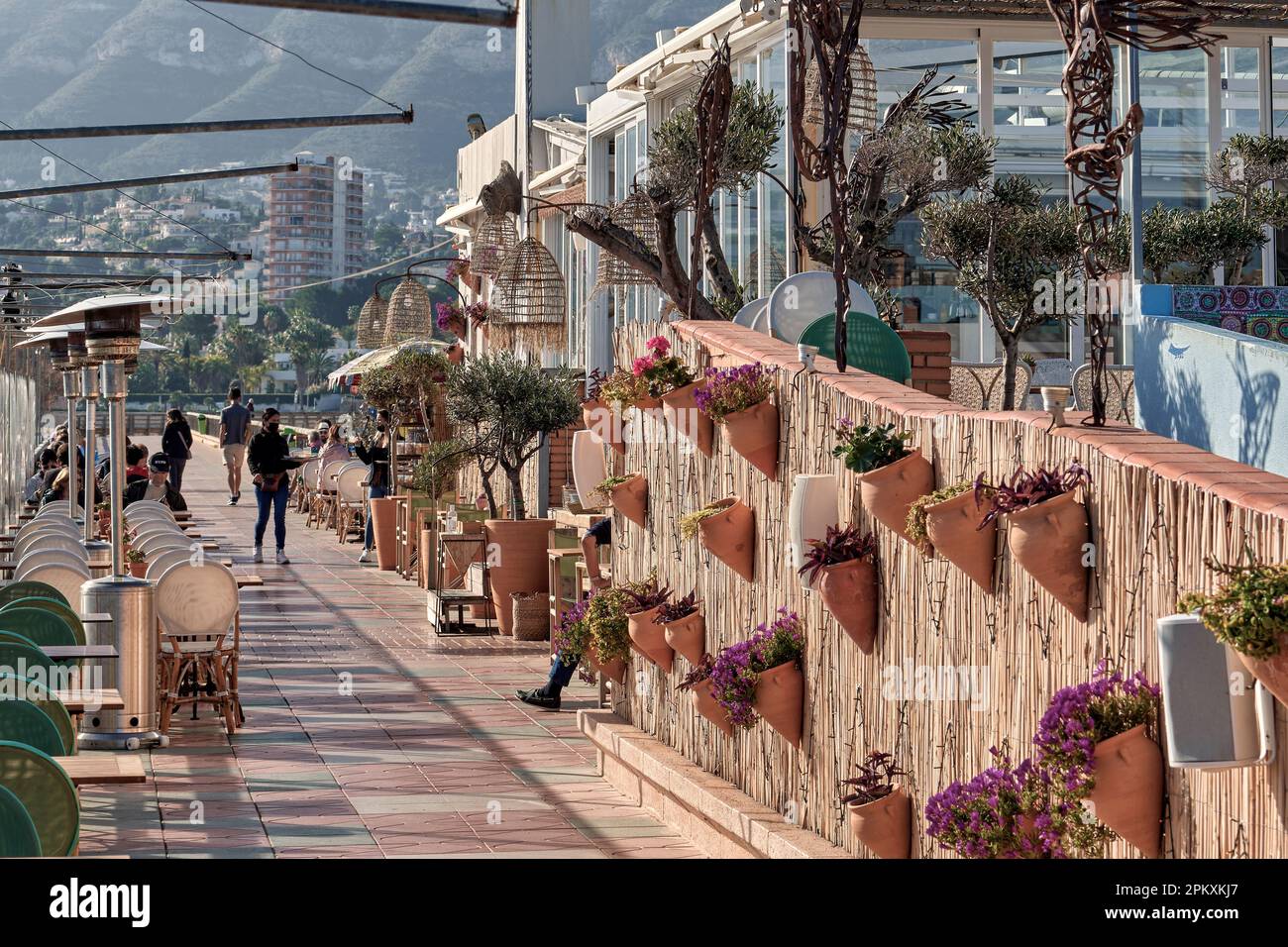 Terrazza piena di turisti che mangiano, seduti sulle sedie e il tavolo nel bar ristorante Mala vita a Marina de Dénia, Alicante, Spagna, Europa Foto Stock