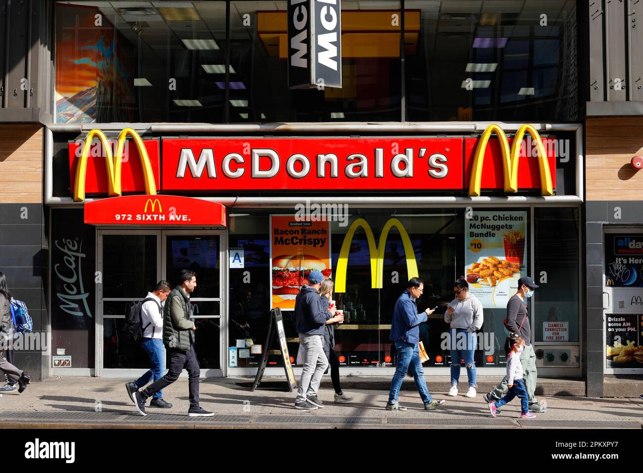 McDonalds, 972 Sixth Ave, New York, foto di fronte al negozio di New York di un turista che cammina davanti ad un fast food in Herald Square di Manhattan. Foto Stock