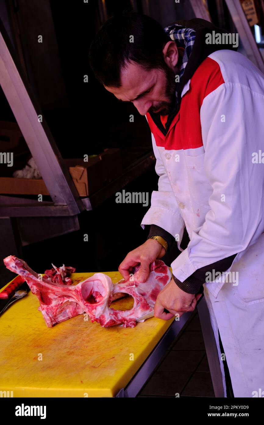 Macellaio rimuove ogni traccia di carne dalle ossa all'interno del mercato di Varvakeios, Atene Foto Stock