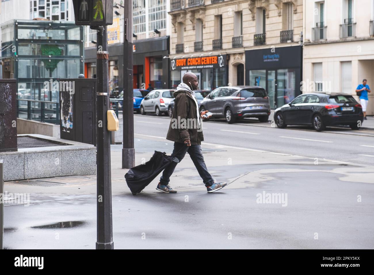 Un uomo nero trascina una borsa su ruote in una strada di Parigi Foto Stock