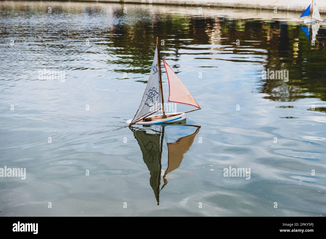 Barca a vela giocattolo con giocose vele dal design facciale su un laghetto con giardino parigino Foto Stock