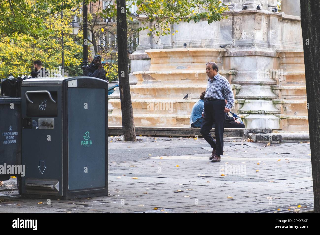 Un anziano uomo cinese attraversa le affascinanti strade di Parigi, ammirando i panorami e i suoni della città dell'amore Foto Stock