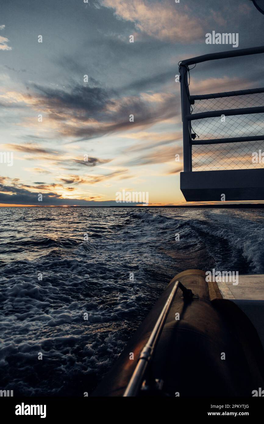 Vista pittoresca della scia di motoscafo nell'oceano contro il cielo nuvoloso durante il tramonto Foto Stock