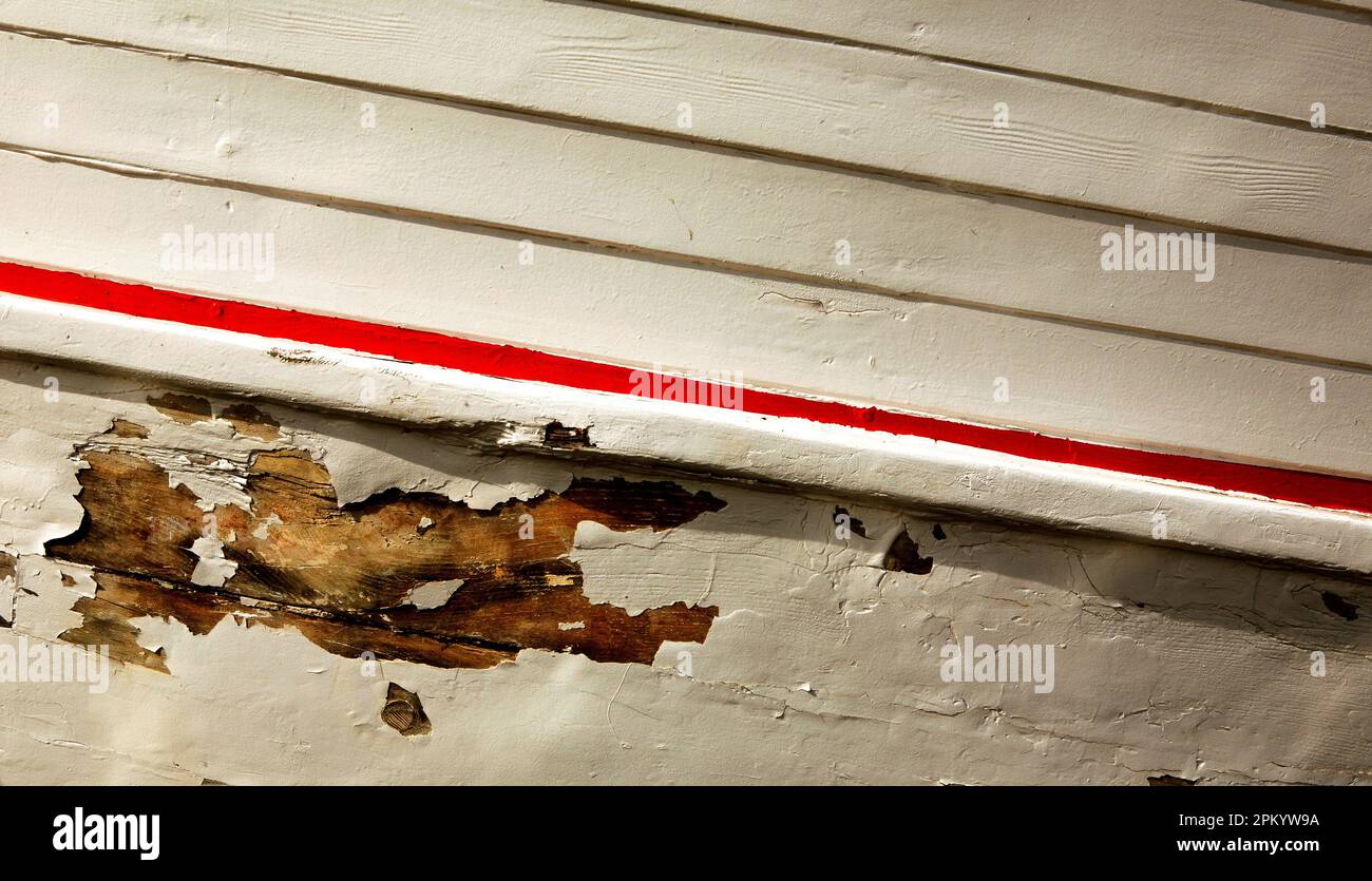 Barca di legno dipinta che ha bisogno di manutenzione perché la vernice è peeling. Foto Stock