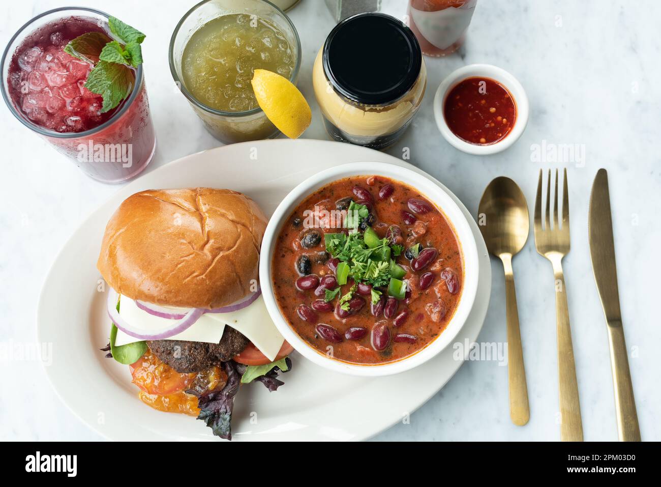 Primo piano di un hamburger, zuppa con fagioli e bevande rinfrescanti sul tavolo Foto Stock