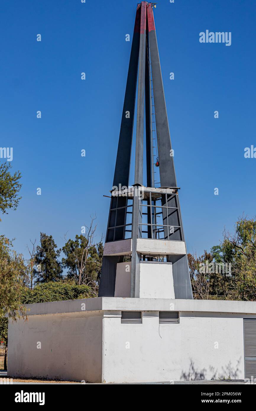 Piccolo edificio con una struttura in acciaio triangolare aperta sul tetto con cielo blu chiaro, alberi verdi sullo sfondo, giorno di sole in Avila Camacho pubblico pa Foto Stock