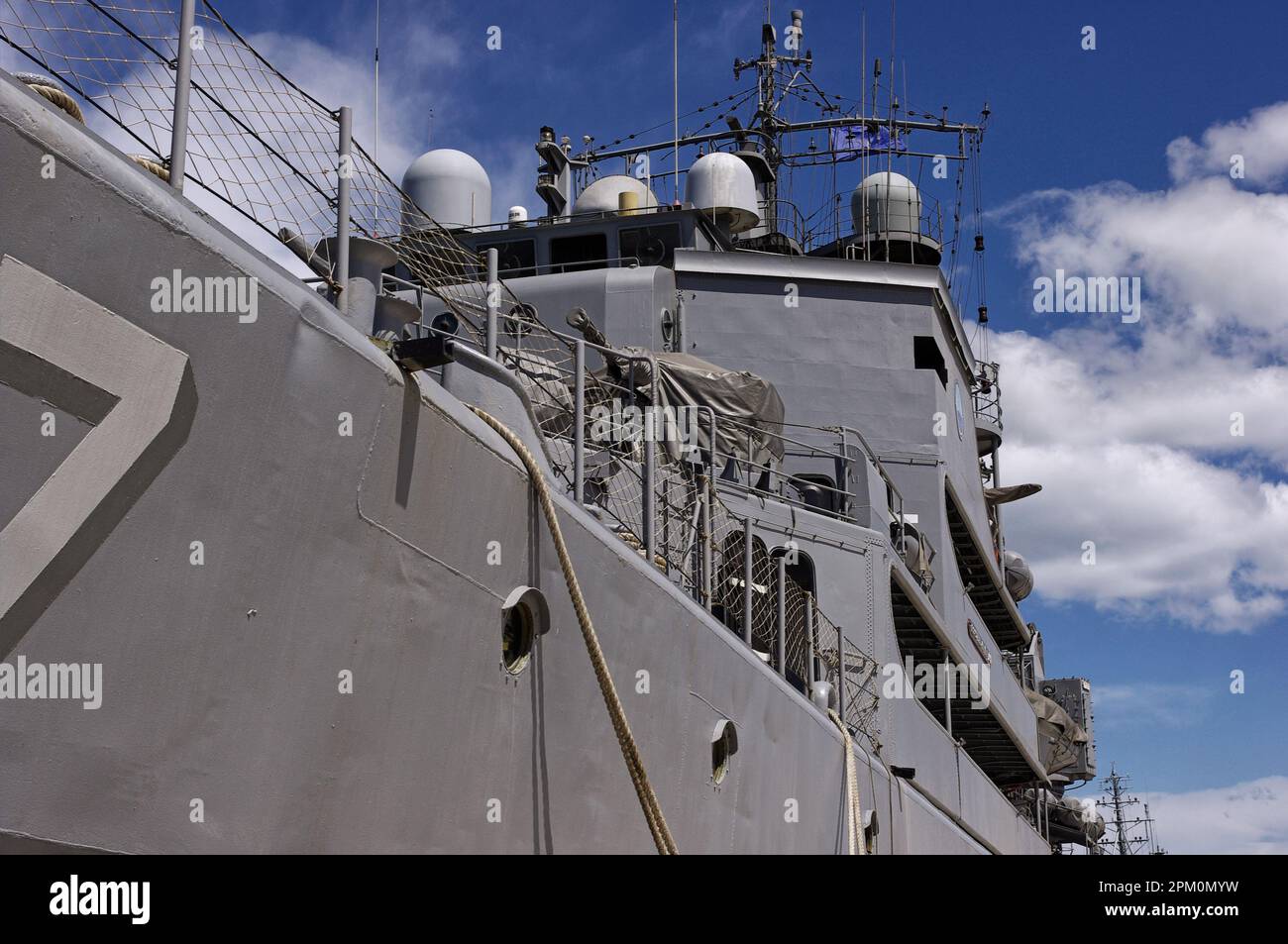 Nave da guerra ormeggiata al porto su cielo blu con nuvole Foto Stock