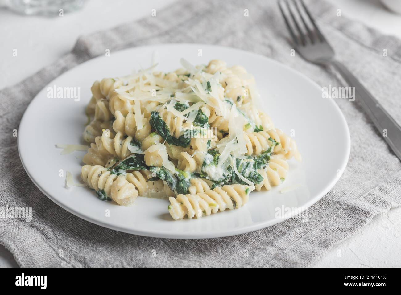 Pasta di fusilli con spinaci e ricotta guarnita con parmigiano grattugiato Formaggio su piatto bianco Foto Stock