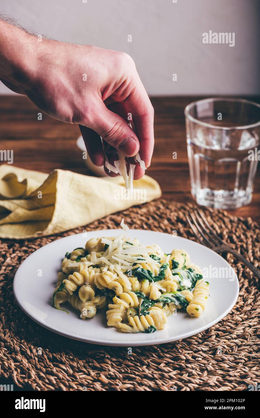 Pasta di fusilli con spinaci e ricotta guarnita con parmigiano grattugiato Formaggio su piatto bianco Foto Stock
