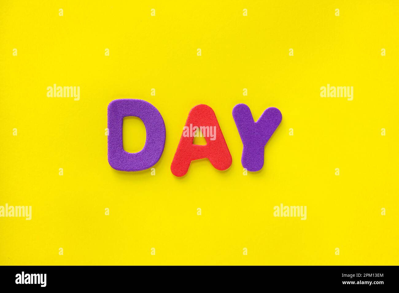 Lettere colorate di testo giorno isolate su sfondo giallo con spazio di copia. Concetto di layout piatto, vista dall'alto, spazio di copia. Foto Stock