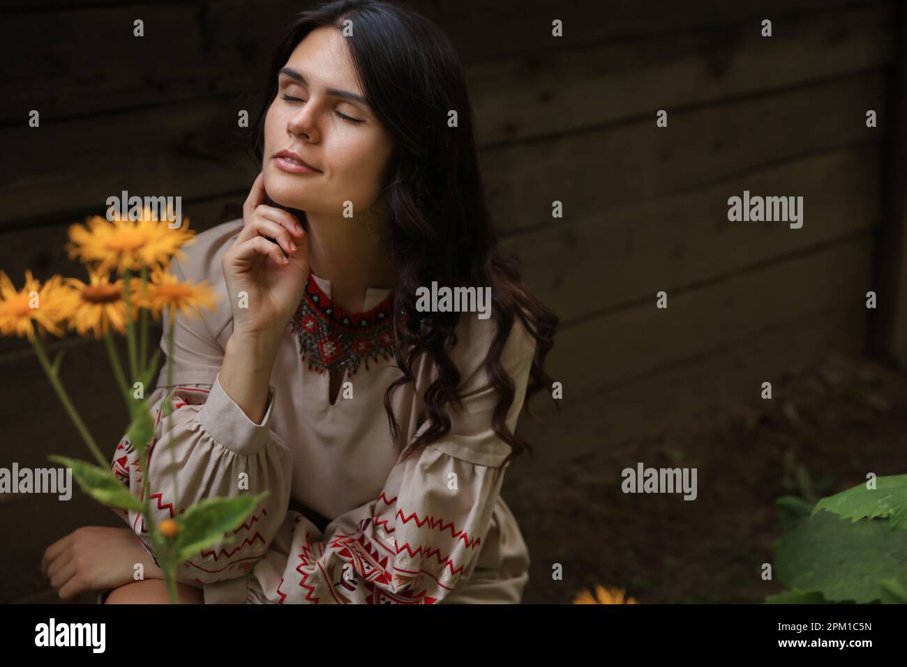 Bella donna vestito ricamato in giardino fiorito, spazio per il testo. Vestiti nazionali ucraini Foto Stock