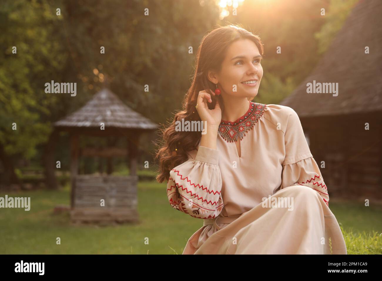 Bella donna vestito ricamato in villaggio il giorno di sole, spazio per il testo. Vestiti nazionali ucraini Foto Stock