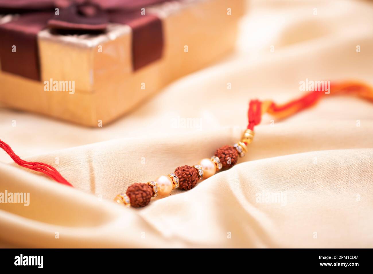 Primo piano del rudraksh rakhi su sfondo dorato Foto Stock