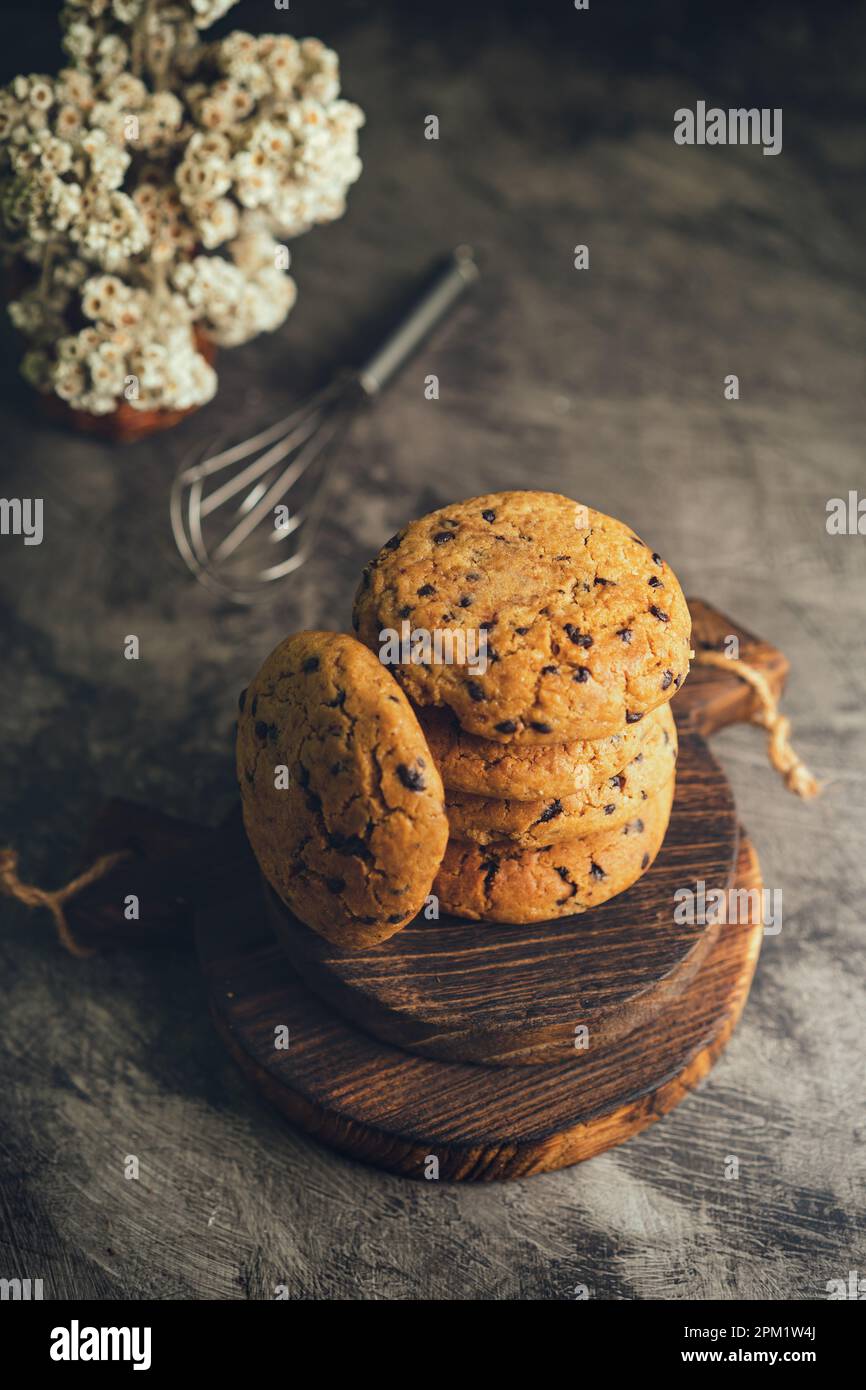 Biscotti fatti in casa con gocce di cioccolato su vassoio refrigerante nero e sfondo astratto Foto Stock