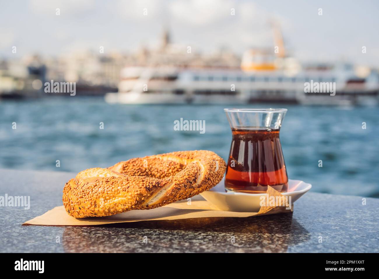 Un bicchiere di tè turco e bagel Simit contro la baia del corno d'oro a Istanbul, in Turchia. Turkiye Foto Stock