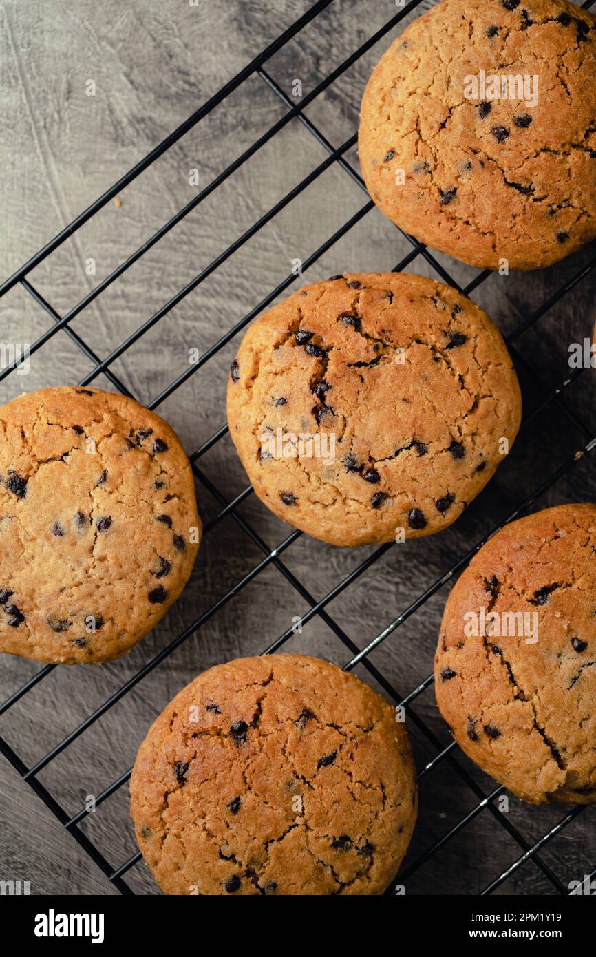 Biscotti fatti in casa con gocce di cioccolato su vassoio refrigerante nero e sfondo astratto Foto Stock