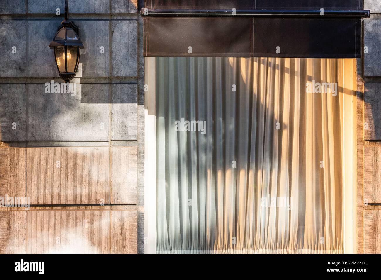 Lampada da parete e finestra illuminata dal sole mattutino che si riflette su lastre dorate. Bruxelles. Foto Stock