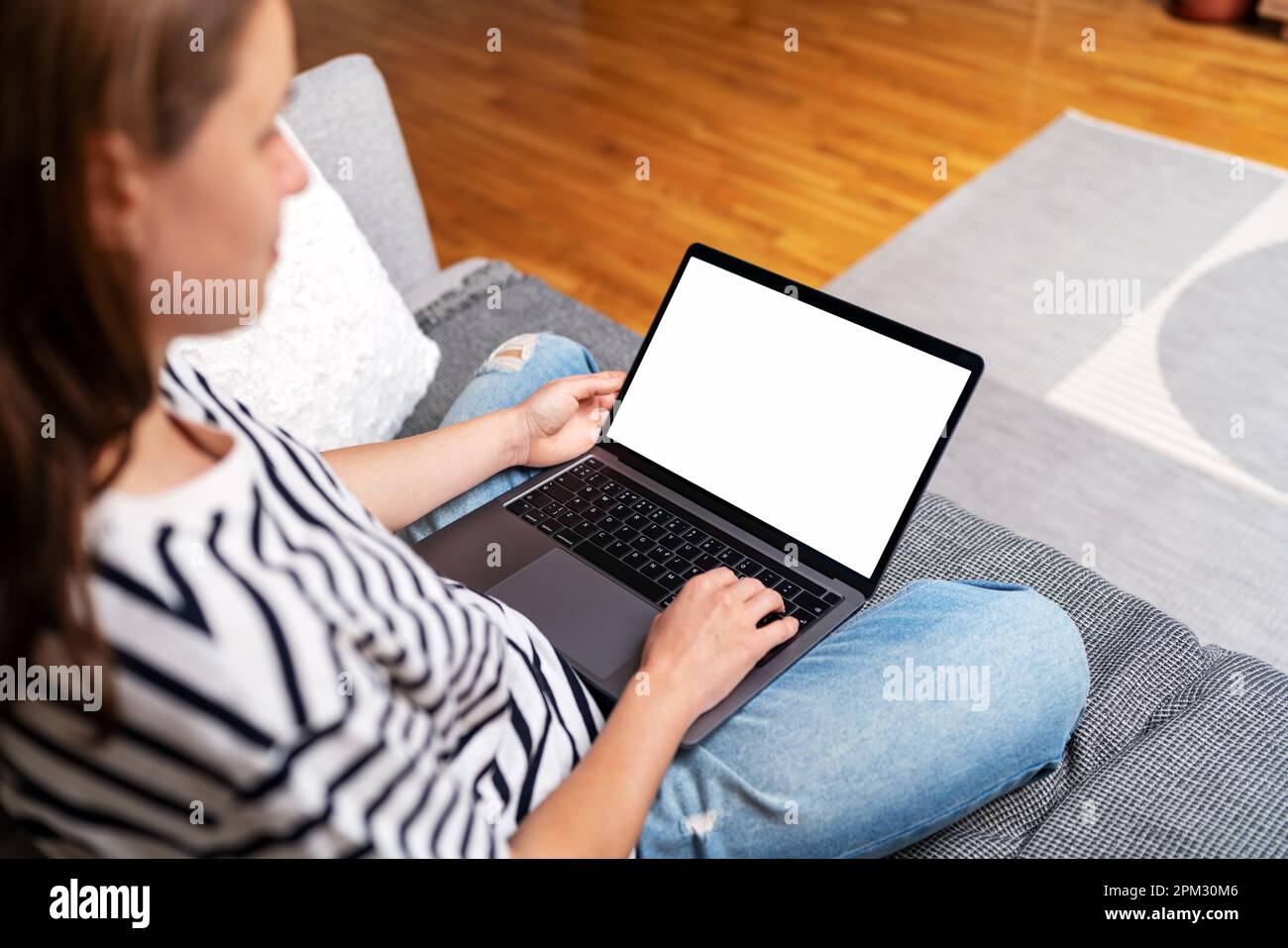 Computer portatile con schermo vuoto, donna che usa il computer portatile a casa mentre si siede sul divano. Foto Stock