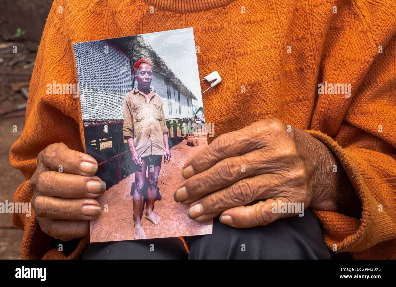 Le mani di una vedova anziana della minoranza etnica Jerai negli Altopiani centrali del Vietnam, tengono una fotografia del suo defunto marito, il villaggio c Foto Stock