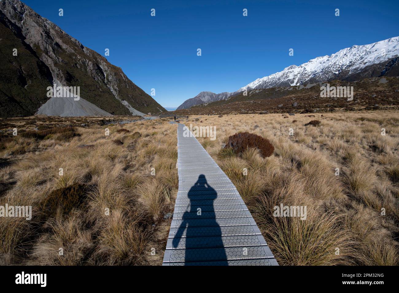 Il Boardwalk percorso con ombra di fotografo con fotocamera, Hooker Valley a piedi, dal Parco Nazionale Aoraki/Mount Cook, Alpi del sud, Canterbury, Isola del Sud, Foto Stock