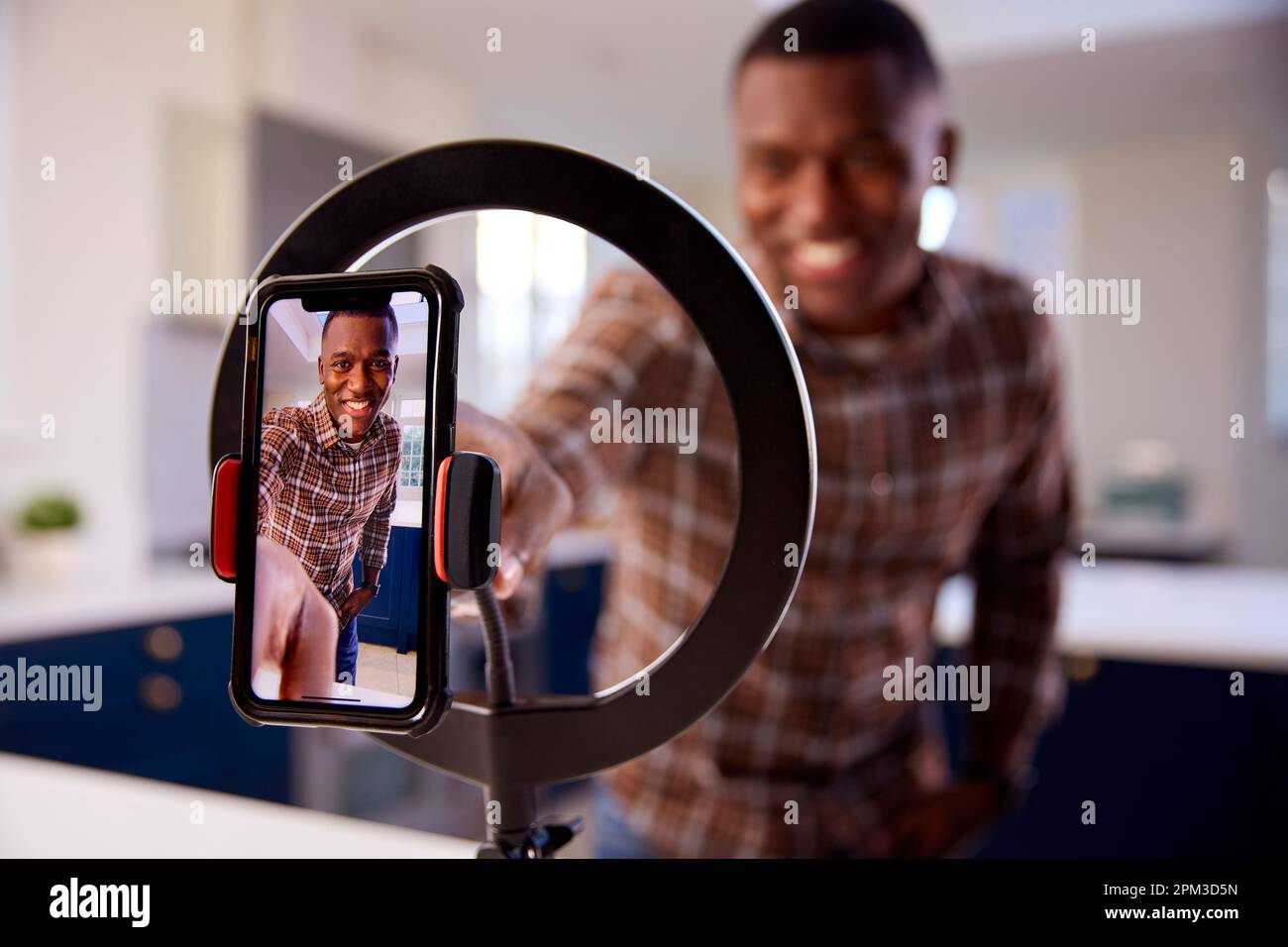 Uomo a casa registrazione video da caricare sui social media sul telefono cellulare Foto Stock