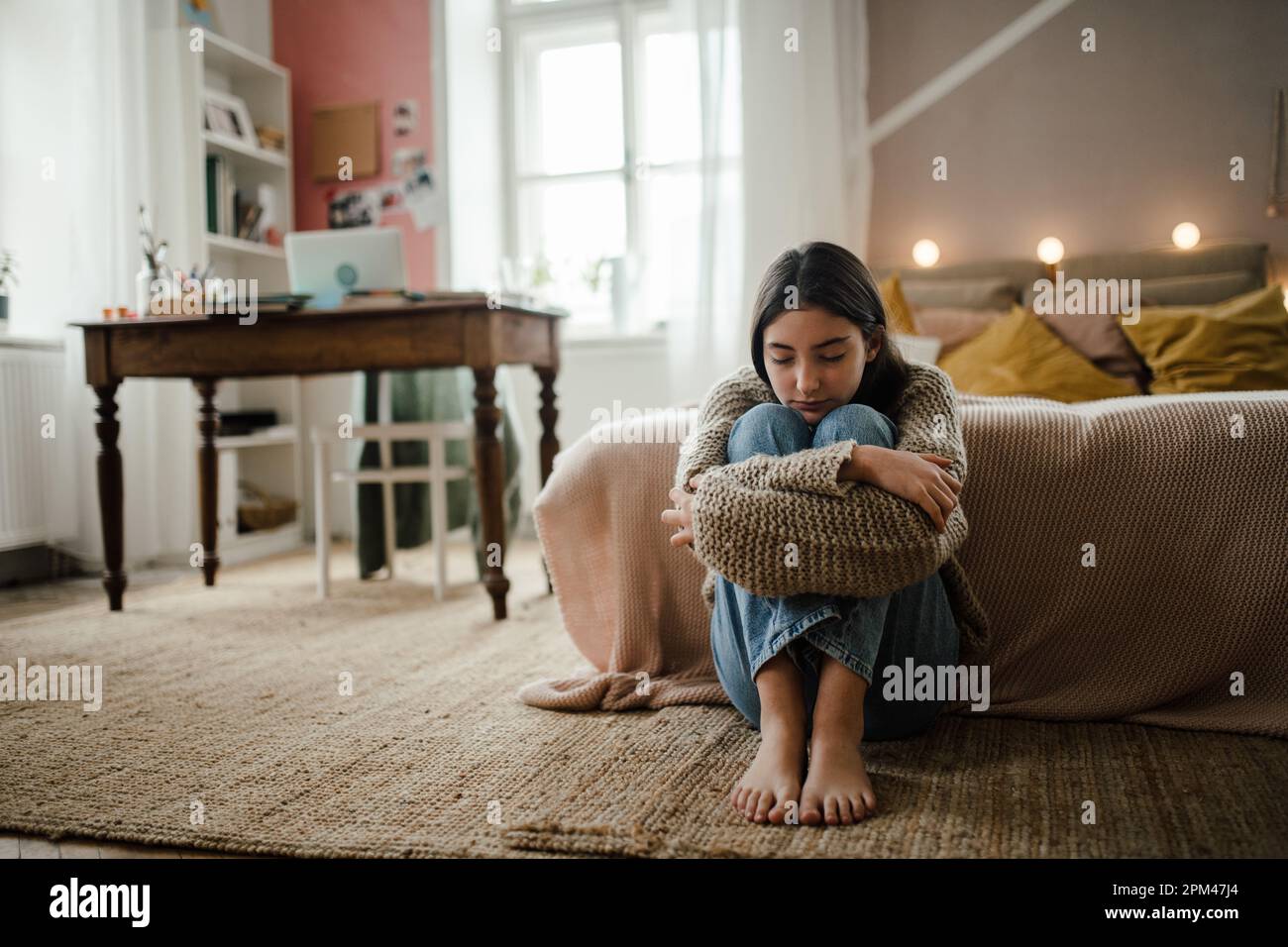 Ragazza adolescente seduta sul pavimento con la testa sulle ginocchia, koncept di salute mentale. Foto Stock