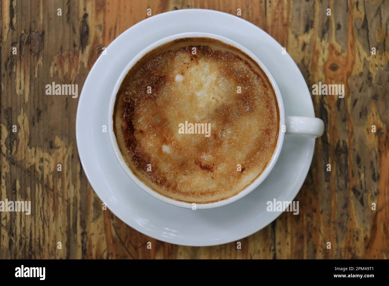 Una tazza di cappuccino su un tavolo di legno con un piano in crème brulee. Foto Stock