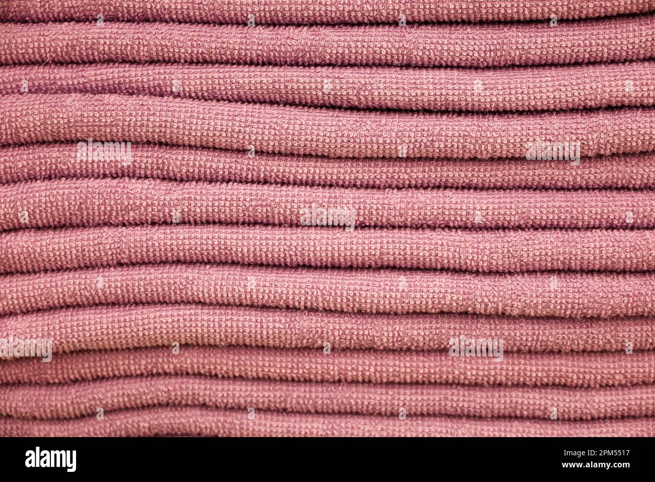 Pila di asciugamani in spugna, messa a fuoco selettiva. Fondo morbido, primo piano in tessuto rosa bagno Foto Stock