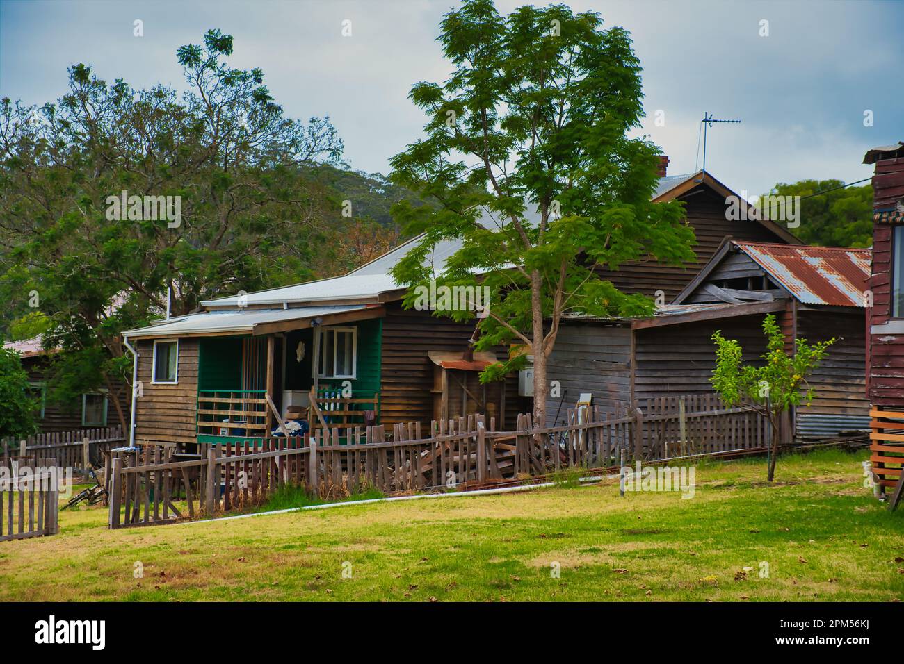 Vecchio, piuttosto trascurato Weatherboard cottage con una recinzione rotta in una piccola città australiana Foto Stock