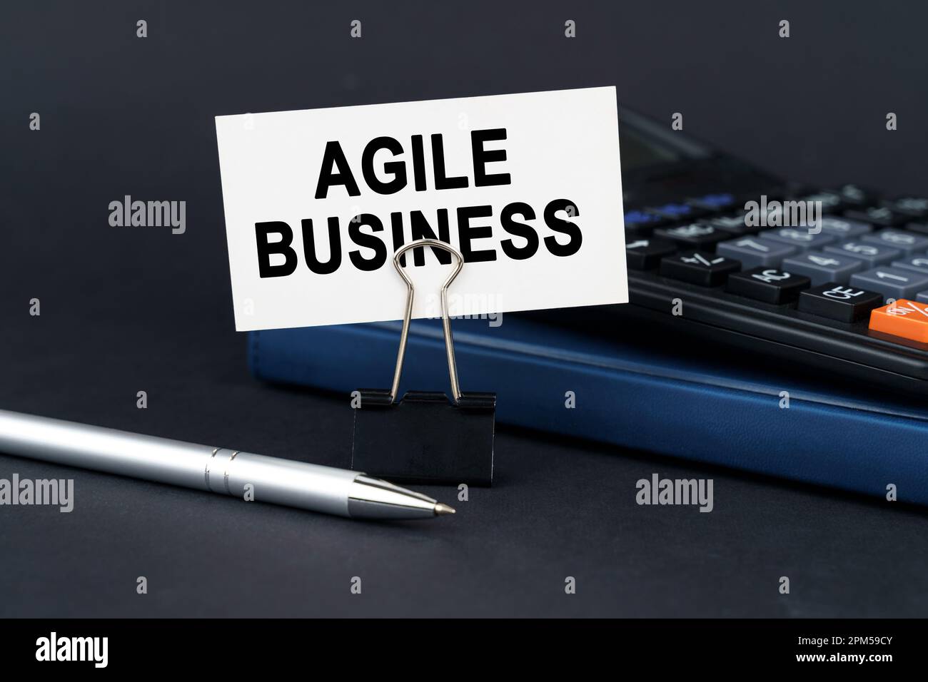 Concetto aziendale. Sul tavolo c'è un notebook, una calcolatrice, una penna e un biglietto da visita con l'iscrizione Agile Business Foto Stock