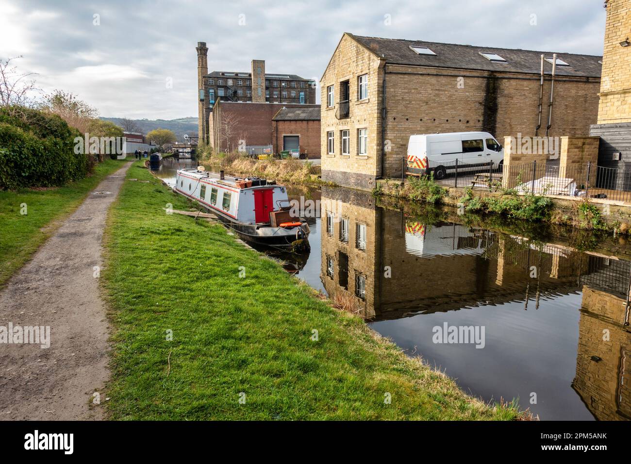 L'Huddersfield Broad Canal con vecchi mulini e magazzini che si riflettono nelle acque fisse – Huddersfield, West Yorkshire, Inghilterra, Regno Unito Foto Stock