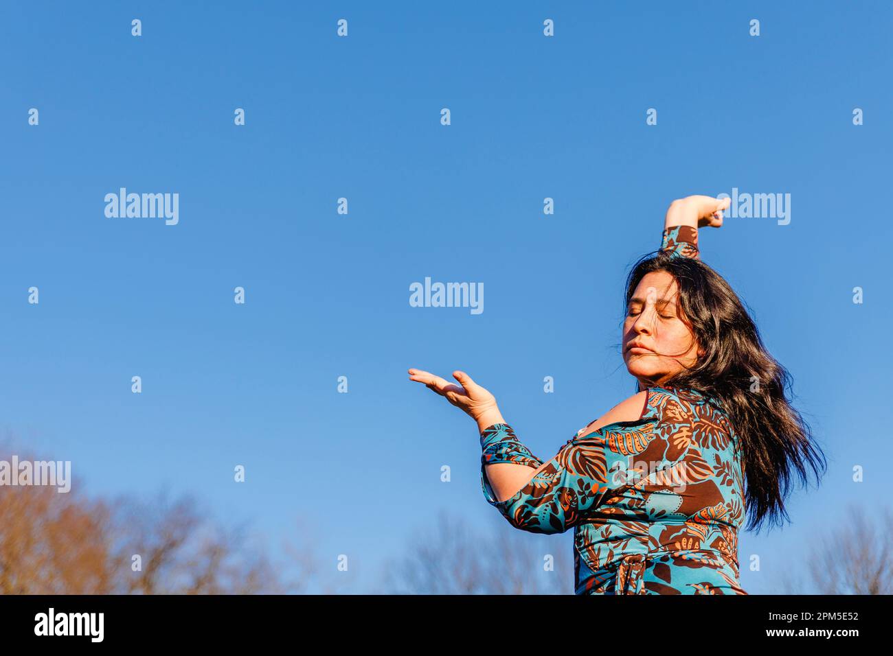 Appassionato ritratto di donna che danza contro il cielo blu Foto Stock