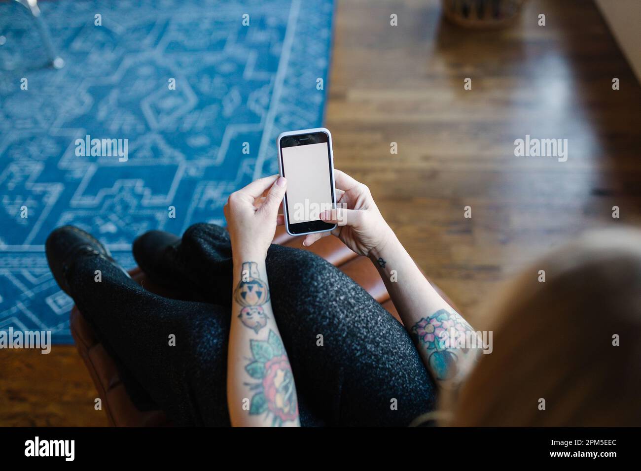 Guardando sopra la spalla di una donna adulta che lavora sul suo smartphone Foto Stock