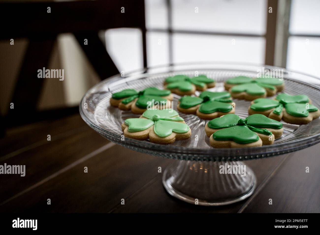 Biscotti Shamrock ghiacciati verdi sulla lastra di vetro alla luce della finestra Foto Stock