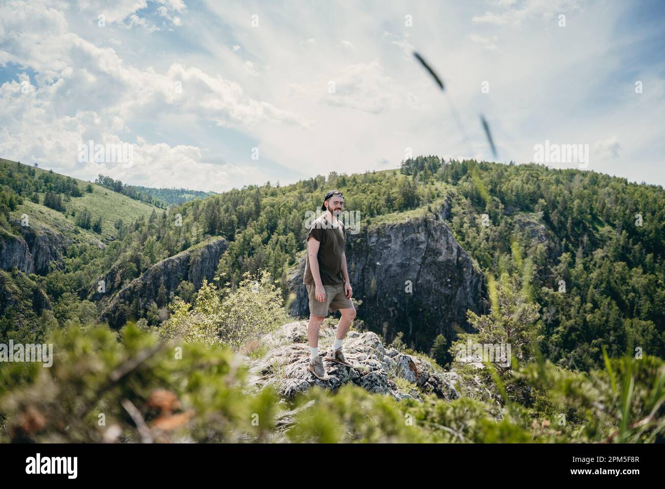 giovane uomo con barba sullo sfondo di un paesaggio montano Foto Stock