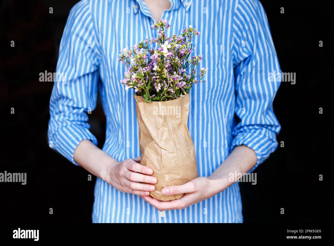 donna in camicia blu tiene il pacchetto di fiori nelle sue mani a casa Foto  stock - Alamy