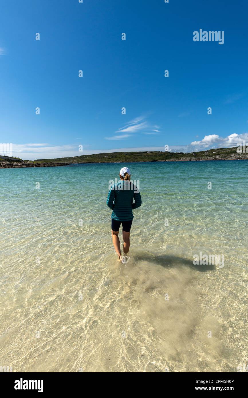 Donna che cammina in acque turchesi limpide a Dog's Bay Foto Stock