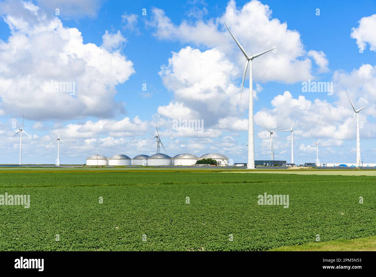 Turbine eoliche, pannelli solari e serbatoi di stoccaggio del combustibile in un parco industriale in una giornata di sole estate Foto Stock
