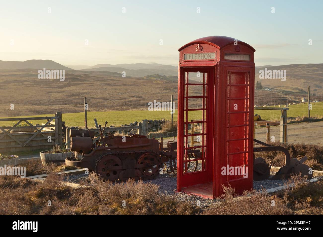Una cabina telefonica rossa ridondante utilizzata come ornamento da giardino in un giardino remoto a Knockarthur, nelle Highlands scozzesi Foto Stock