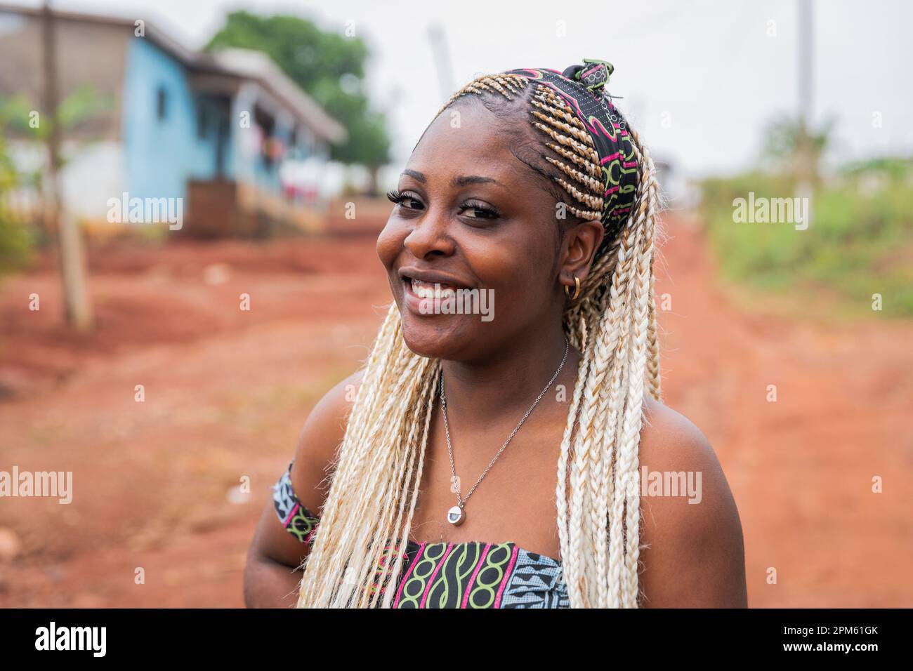 Ritratto di una ragazza africana sorridente con trecce e abiti tradizionali Foto Stock