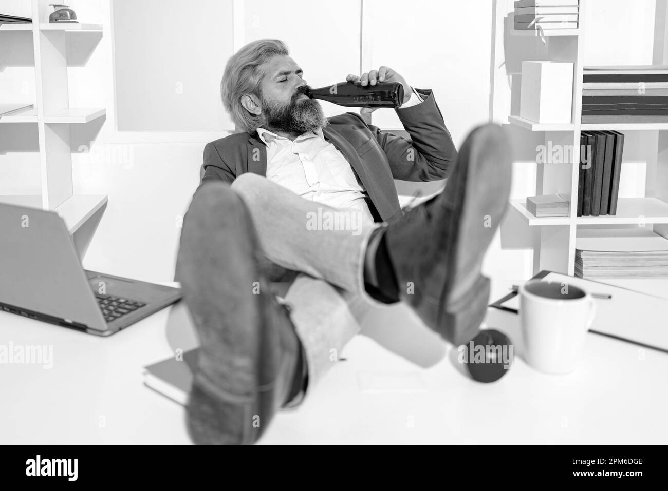 Uomo d'affari che beve birra in ufficio, grandangolo. Uomo d'affari pausa per rilassarsi. Lavoratore divertente. Divertente lavoro di ufficio che va pazzo di alcol. Ubriaco addicted Foto Stock