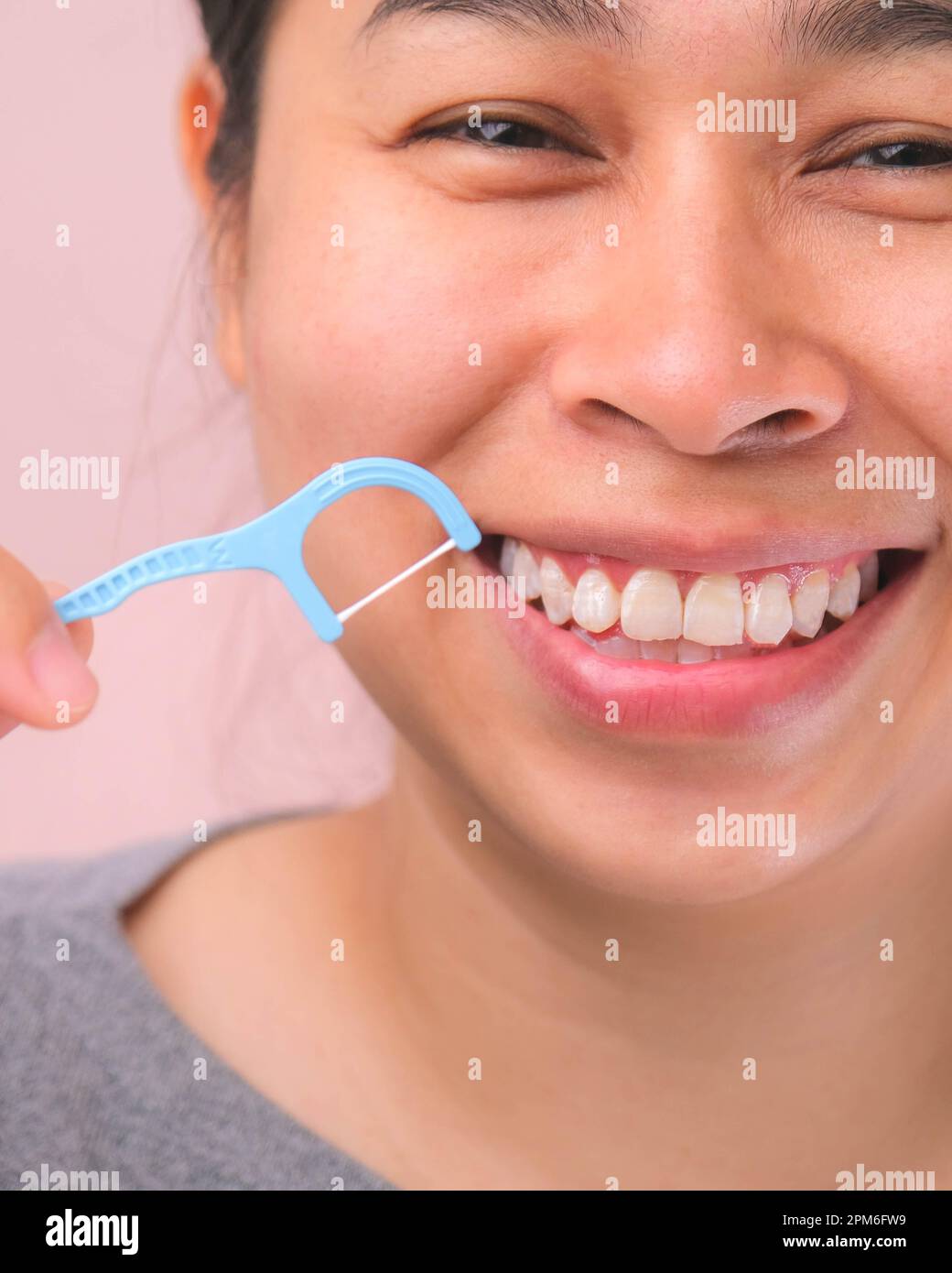 Primo piano di una donna asiatica sorridente e pulizia per un sorriso perfetto. Denti bianchi sani da filo interdentale, salute orale e cura dentale. Foto Stock