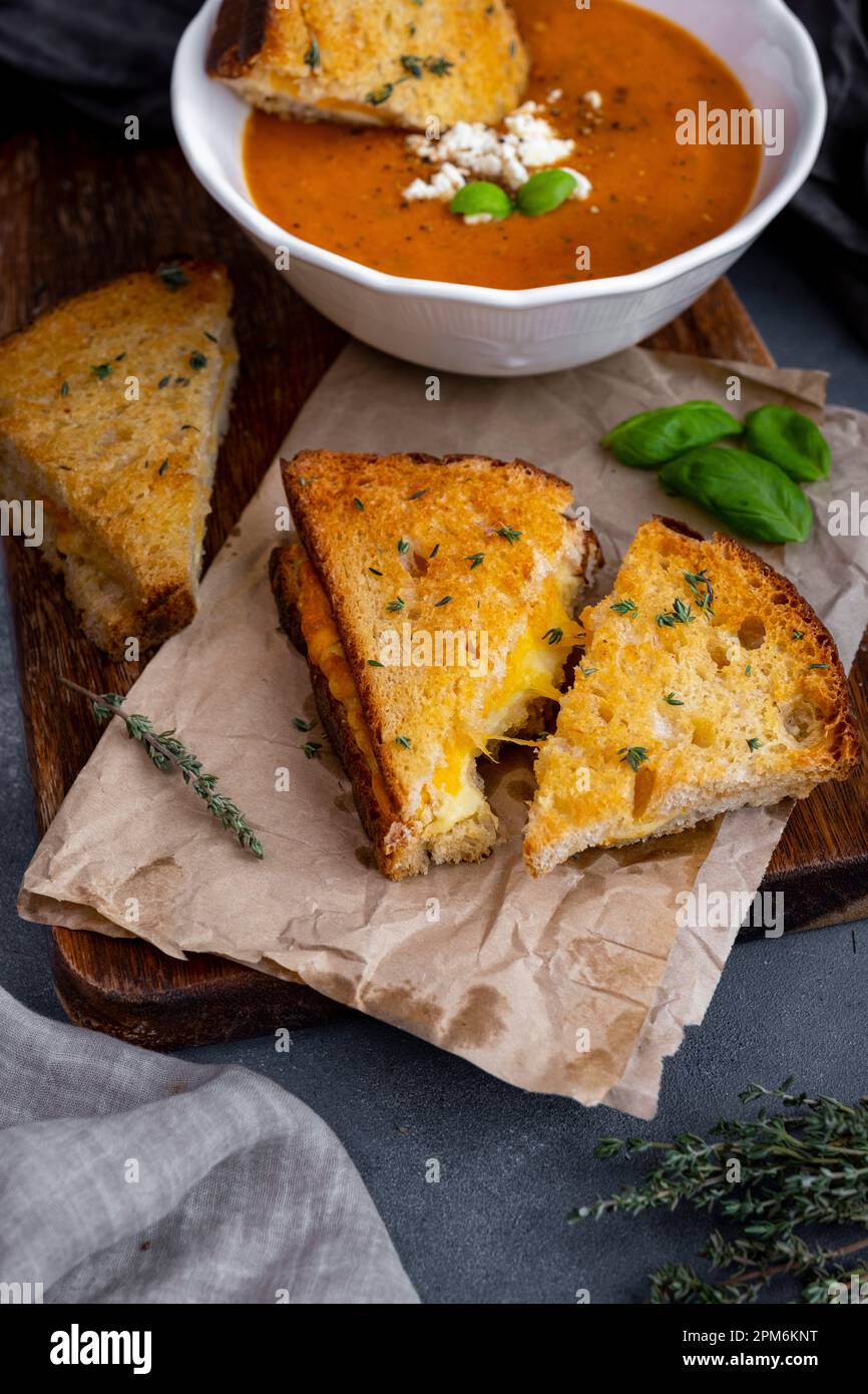 Panini al formaggio alla griglia guarniti con timo e una ciotola di zuppa di pomodoro dietro di loro. Foto Stock