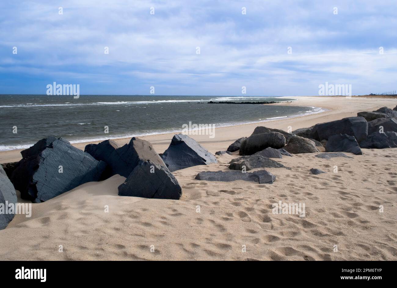 Spiaggia di sabbia con massi sull'Oceano Atlantico. Cielo blu con nuvole spionate in un giorno d'inverno, Sandy Hook Beach, New Jersey, USA, parte di Gateway nati Foto Stock