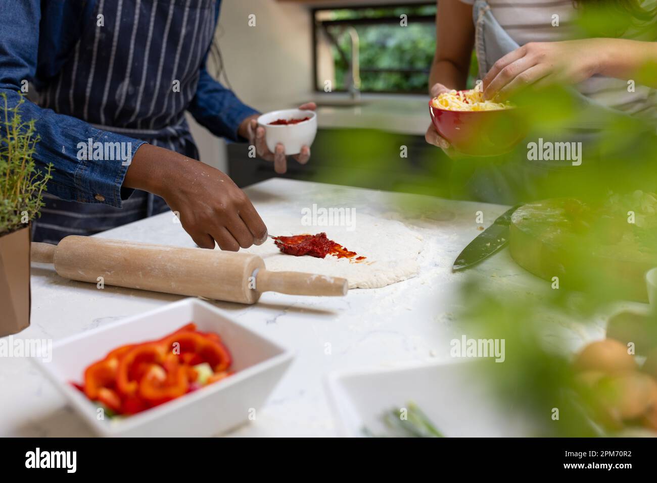 Metà di diverse ragazze adolescenti amici fare la pizza in cucina Foto Stock