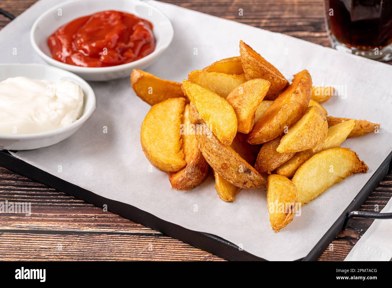 Spicchi di patate con ketchup e maionese su tavolo di legno Foto Stock