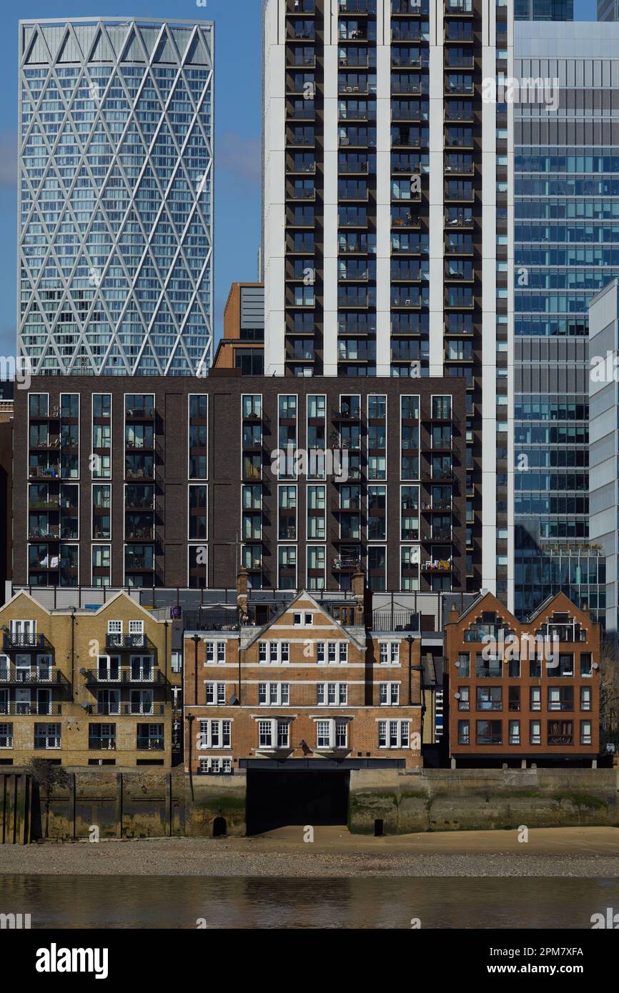 I grattacieli di Canary Wharf, parte del quartiere centrale degli affari di Londra, dominano in primo piano le vecchie abitazioni lungo il fiume Tamigi. Foto Stock